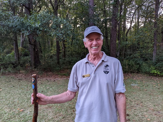 Man in volunteer uniform with hiking stick, forest in background