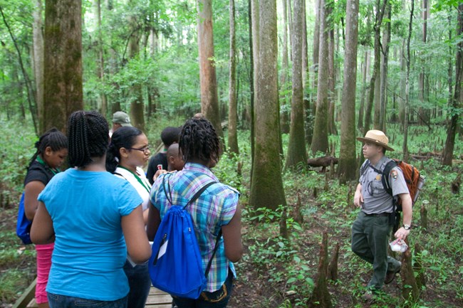 Students listening to ranger give instruction next to a tree
