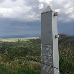 An obelisk marking the US-Mexico border with hills in Mexico in the background