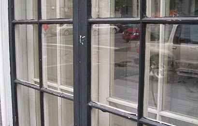 Close-up of the exterior of a window painted dark gray and with peeling paint.