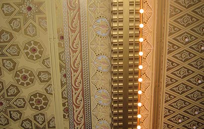 Mechanical ductwork installed in a way that makes it recede from view in an elaborately painted ceiling.