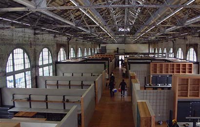 Interior of an industrial building rehabilitated into an office, with exposed mechanical ductwork and roof trusses.