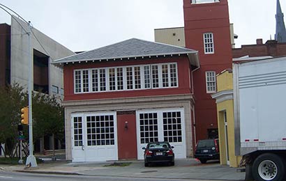 Panel in sidewalk to provide access to a geothermal heating system for the brick building behind it.