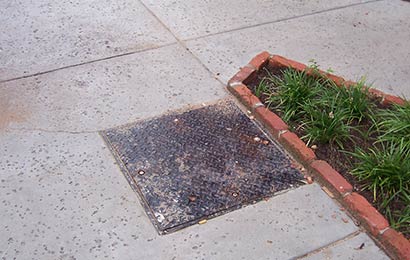 Close-up of a panel in the sidewalk that provides access to a geothermal heating system.
