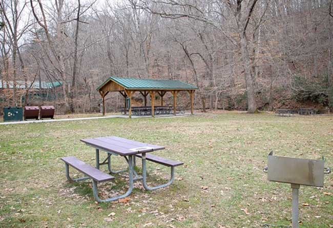 Side angle view of Bartlett Park Picnic Shelter showing recycle bins, trash receptacles.