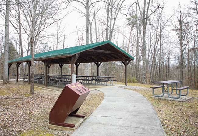 O-4 Picnic Shelter showing a spare picnic table and trash receptacles.