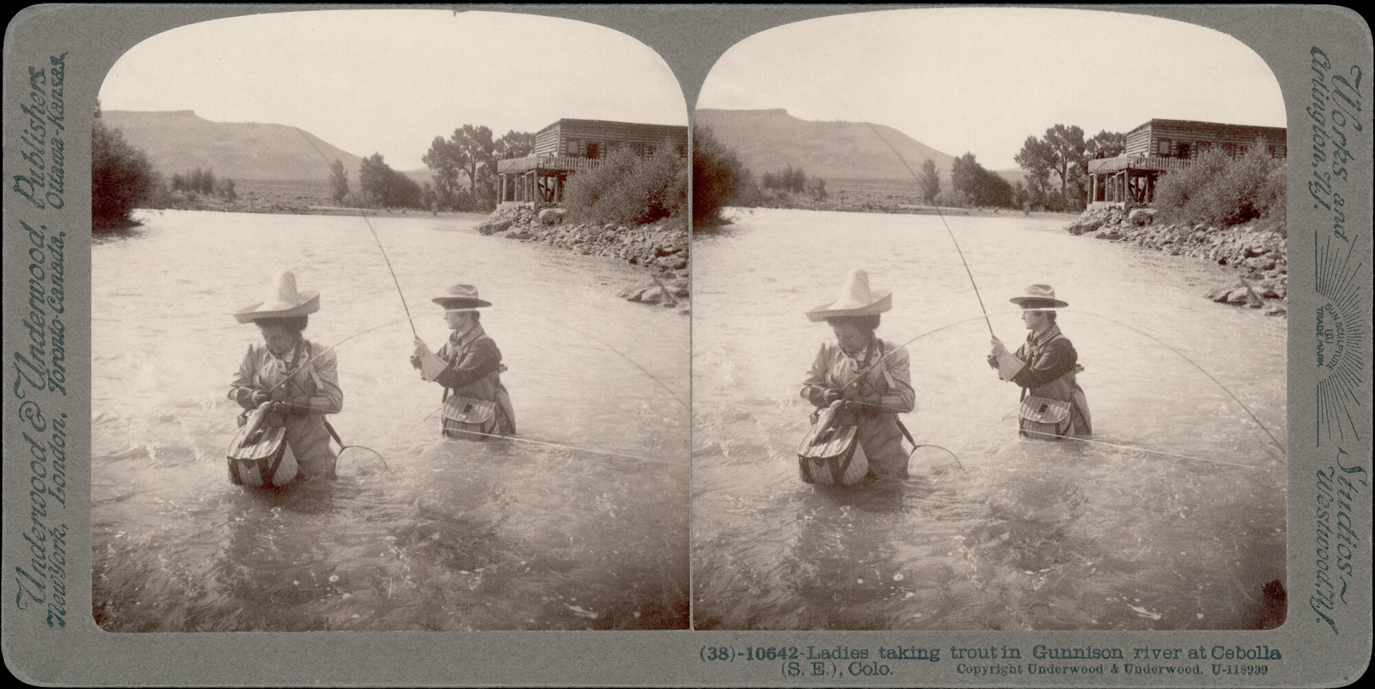Historic stereograph of women fishing in a river. A building and large mesa are in the distance.