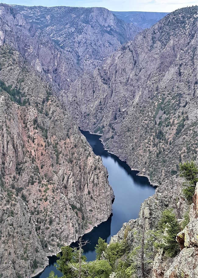A view from an overlook into a narrow reservoir within a deep canyon