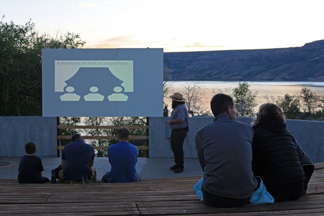 A dimly lit image of a ranger program at an amphitheater