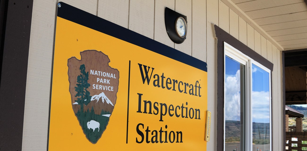 A yellow sign with 'Watercraft Inspection Station' and an arrowhead on it