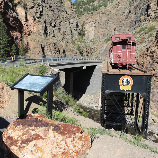 An engine on a truss supsended away from a road with a wayside exhibit