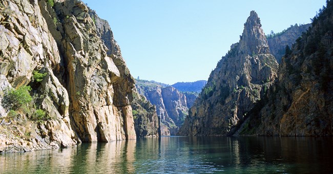 Tall pinnacle next to canyon walls. Water flows between the sides of the canyon,