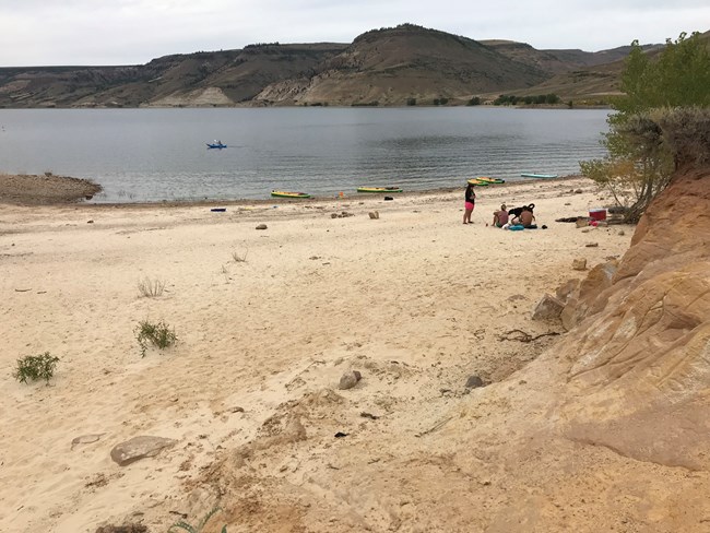 A group of visitors set up on a sandy beach near water