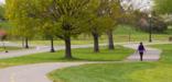 A person walks on a curving, paved trail in Anacostia Park