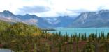Fall colors dot a landscape with towering mountain peaks and turquoise lakes in Lake Clark National Park and Preserve.