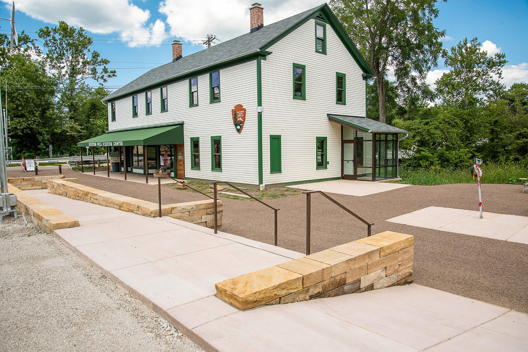 Two-story white building with green trim and a green awning that reads "Boston Mill Visitor Center."