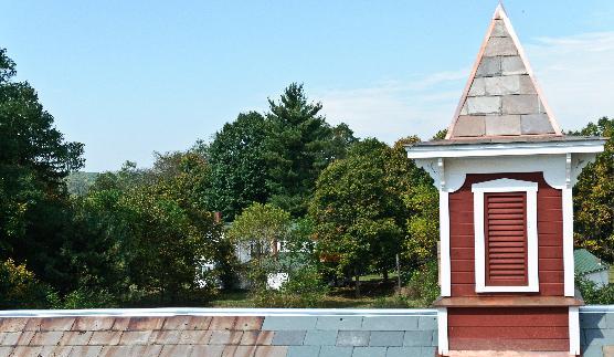 Brown-Bender barn with farmhouse in background on a sunny summer day