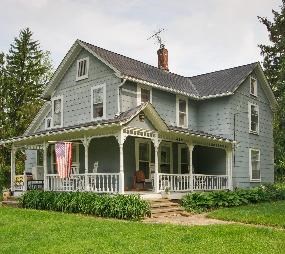 A blue farm-style, two-story house with a large porch and a chimney, the former Goatfeathers Point Farm.