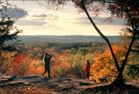 Visitors enjoying the sunset and colorful trees at the Ledges Overlook in the fall