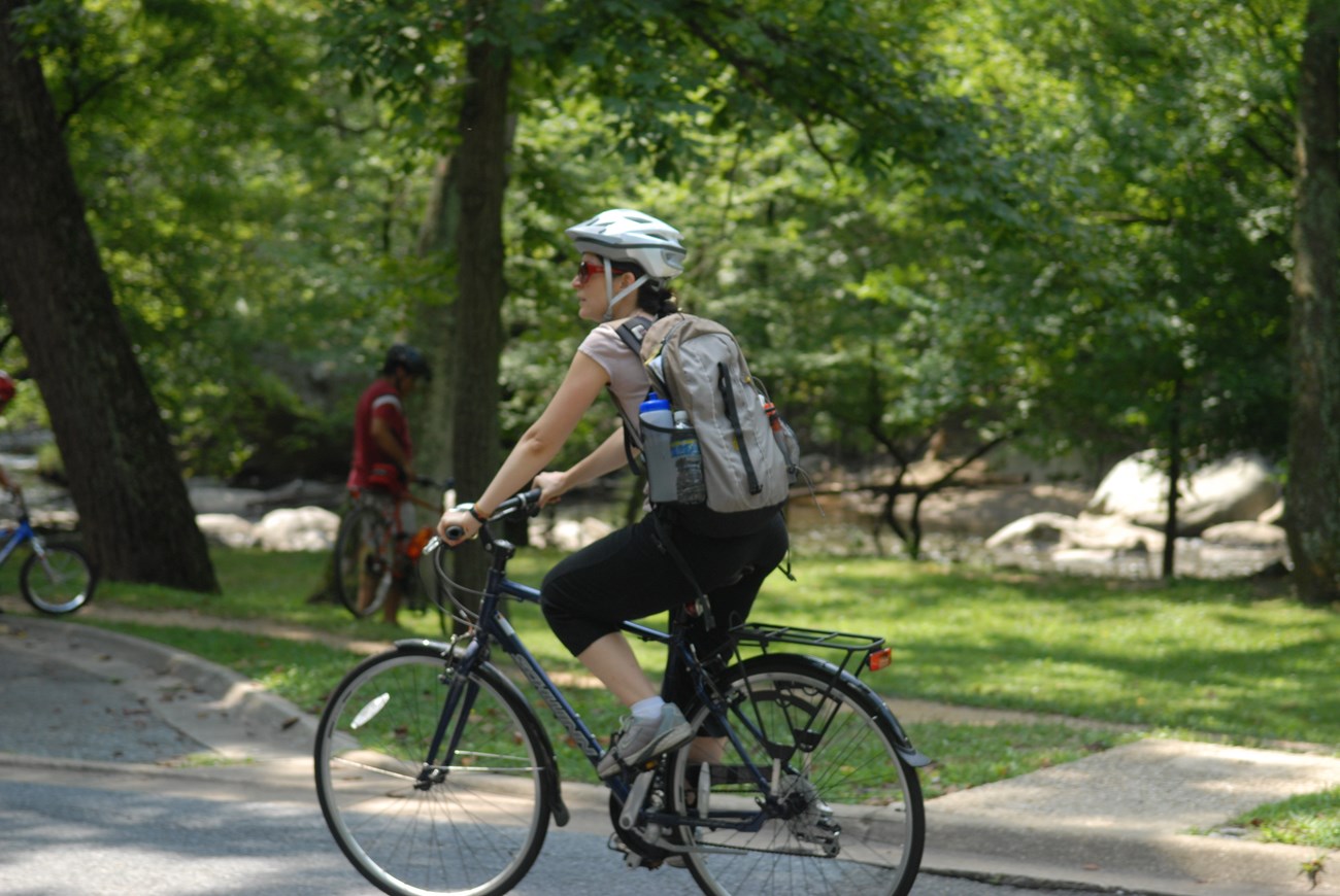 A visitor riding her bike through a National Park.