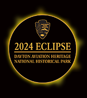 NPS arrowhead and park name within a ring representing the eclipse.