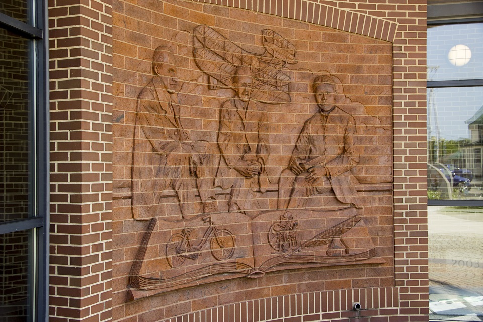 Brick wall at the park's visitor center building showing the images of three men etched into the brick's facade.