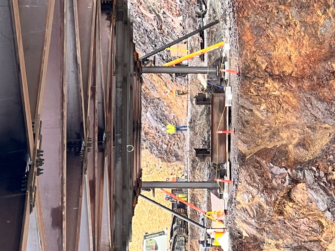 A view underneath the bridge looking toward the west receiving tower. The west end of the bridge is supported by two vertical beams holding it several feet above the abutment.
