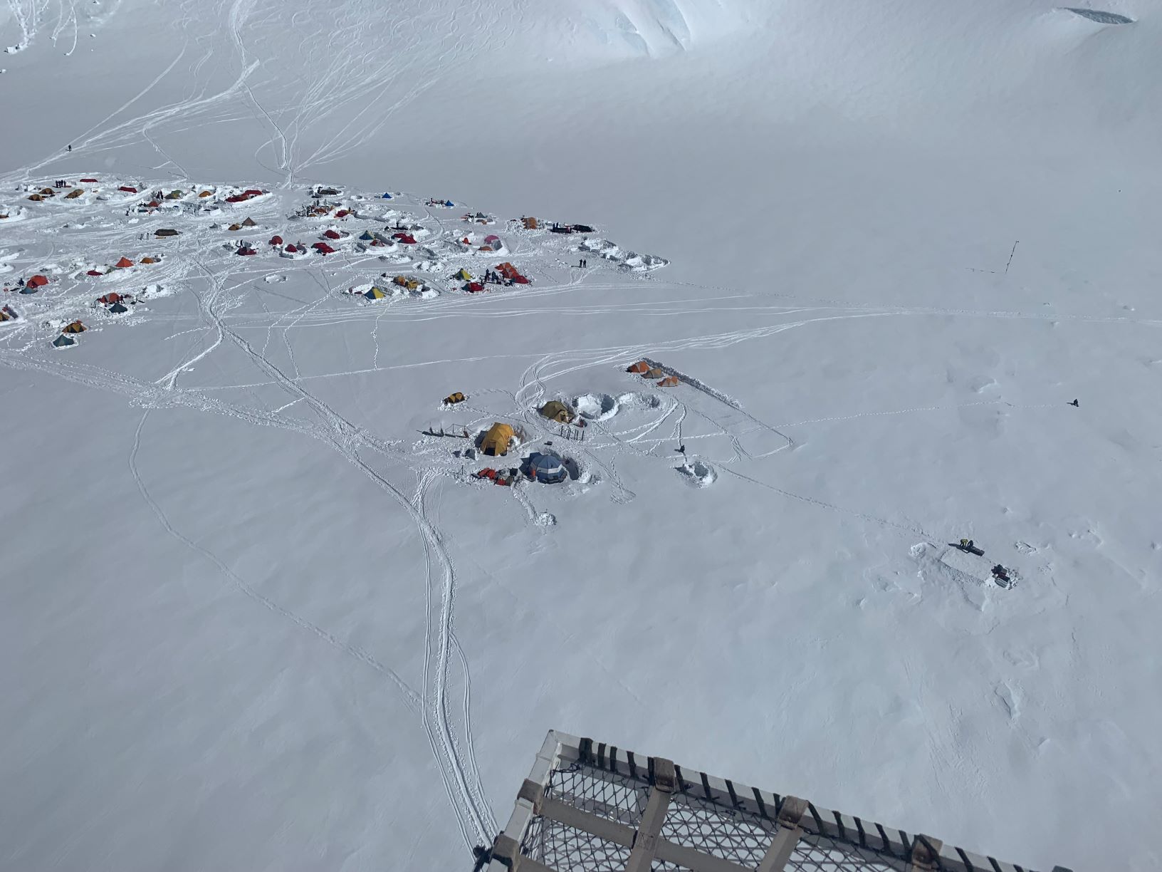 Aerial view of a busy tent village on a snowy glacier