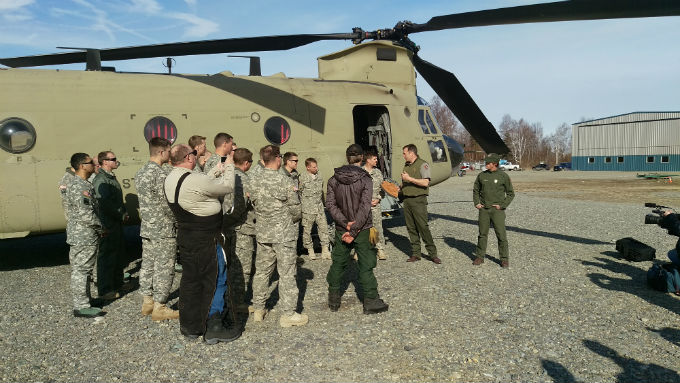 Rangers and military personnel standing outside a CH-47 helicopter.