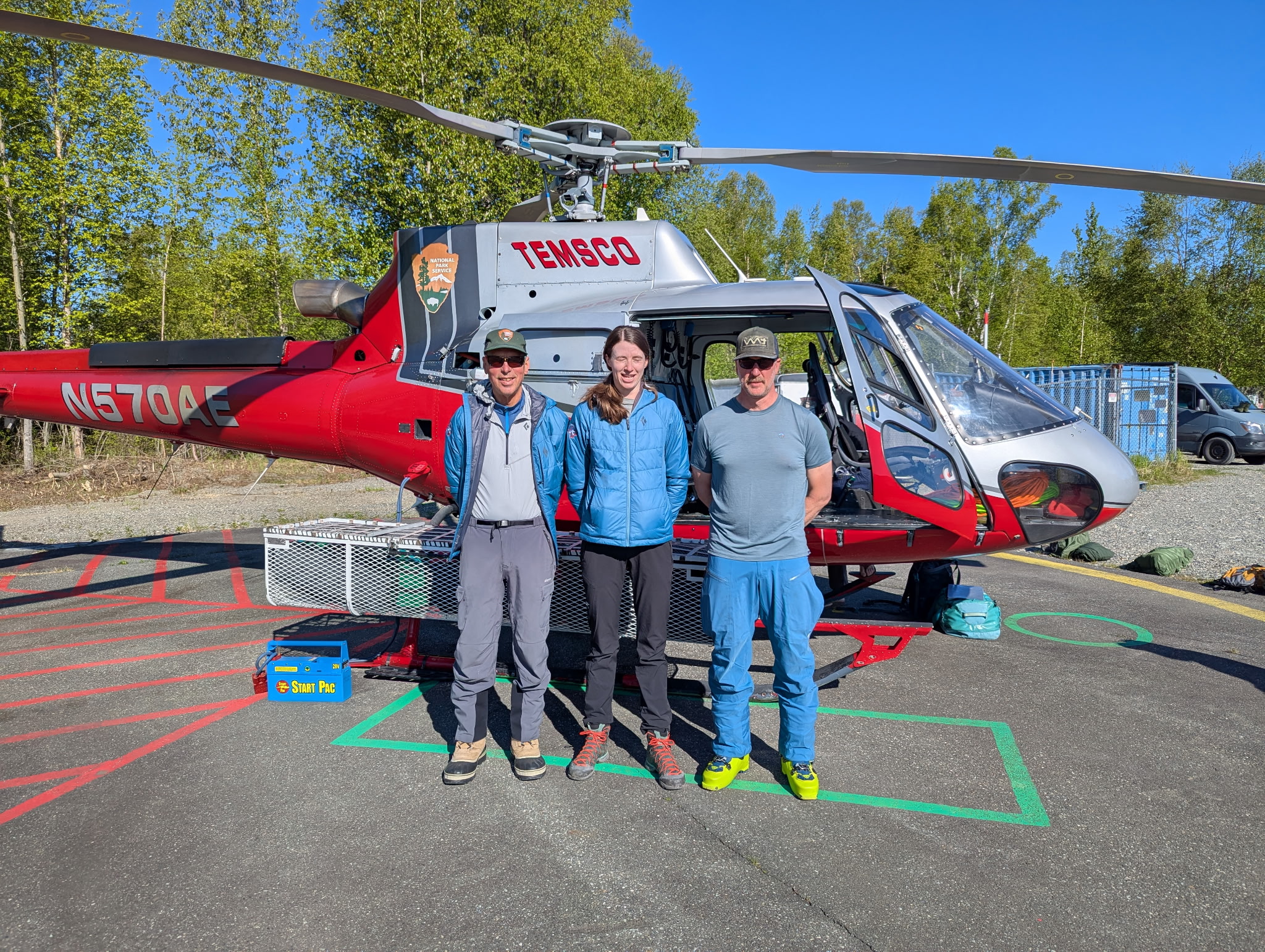 3 rangers stand in front of a red helicopter