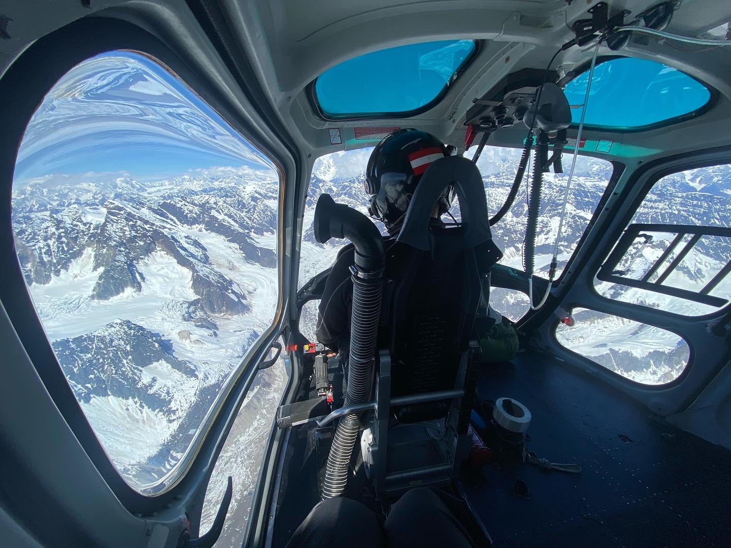 Wide angle view from inside a helicopter flying into the mountains