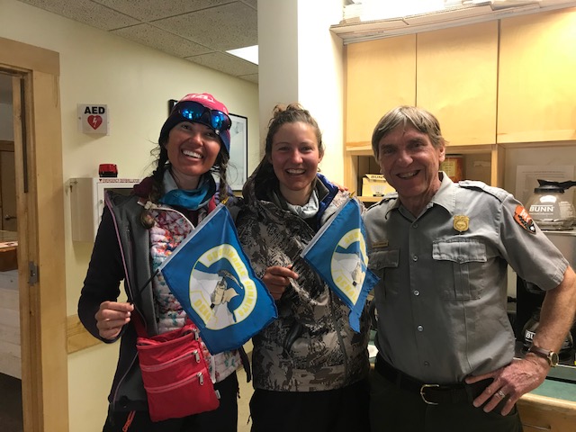 Two mountaineers recently back from Denali display their Sustainable Summits flag for packing out all human waste