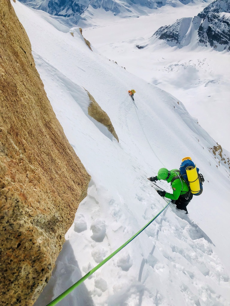 Two roped climbers descend a steep face