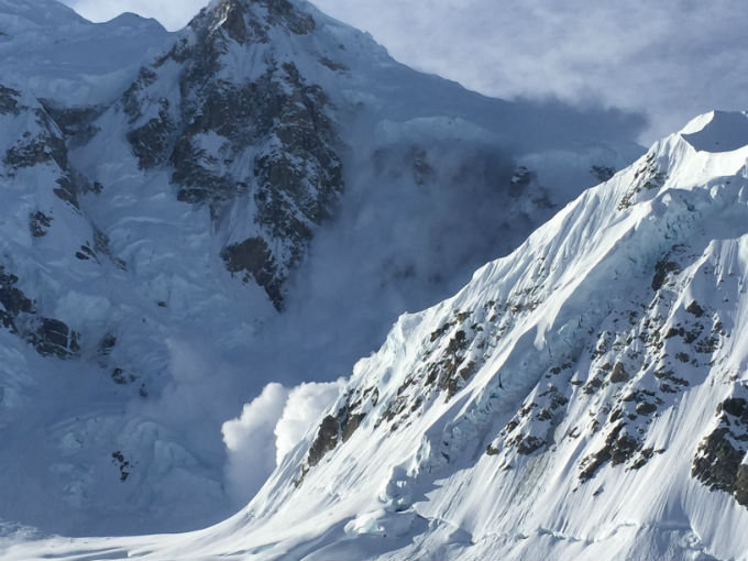 An avalanche cascades off a mountain face