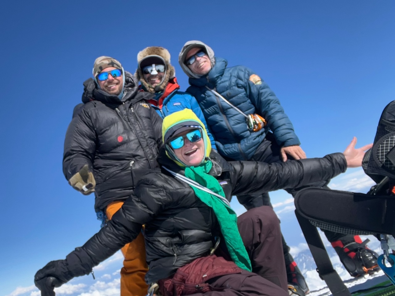 Four cold, smiling faces standing on the summit of North America's highest peak