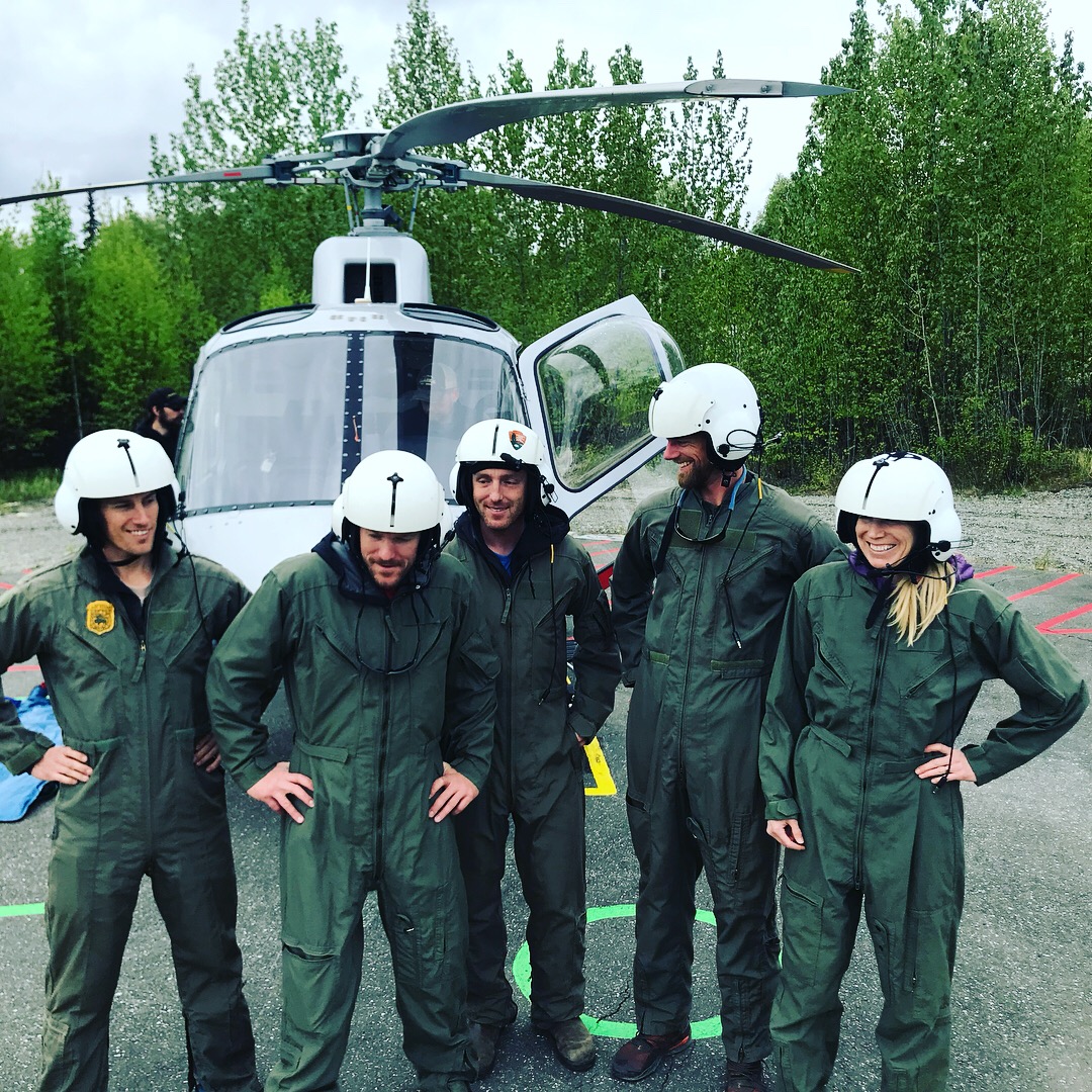 Five volunteers in flight suits take a break during helicopter training