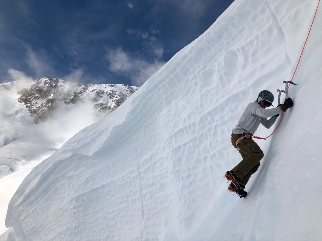 A roped ice climber digs into a steep face