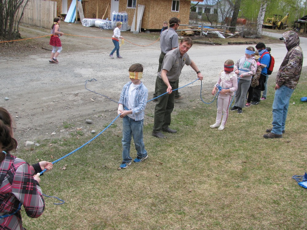 Blindfolded kids walk on a rope line