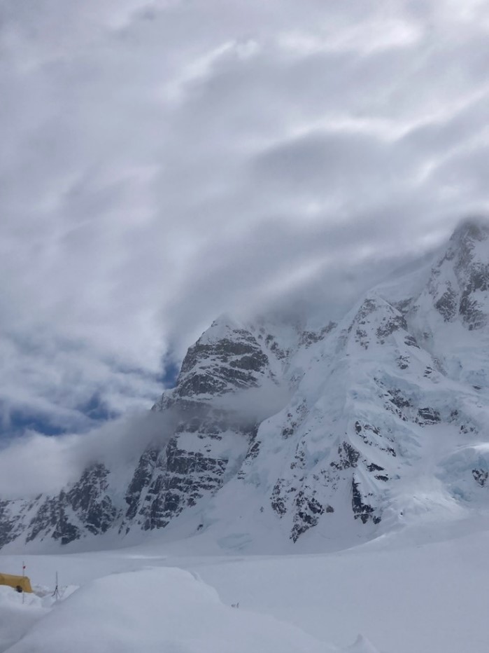 Mountain range covered in snow and surrounded by clouds. 
