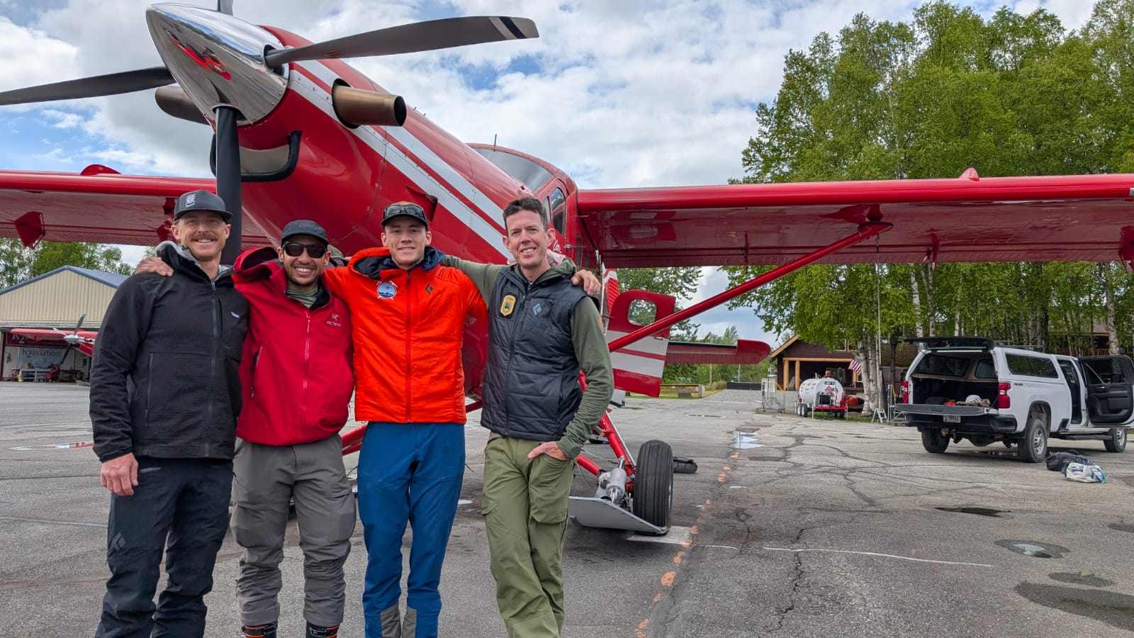 4 rangers stand arm in arm in front of a red plane
