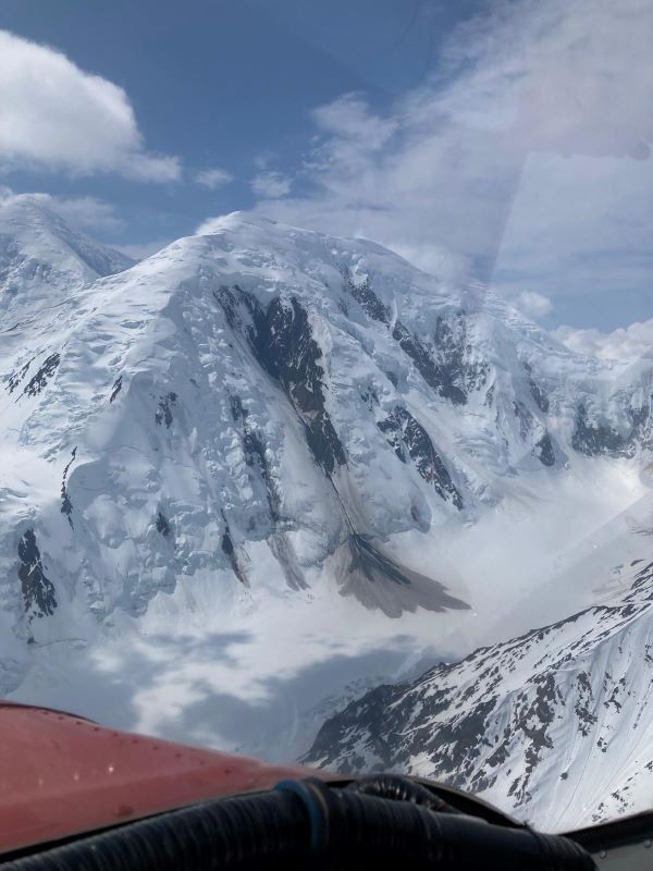 View of a mountain peak out the window of a red plane