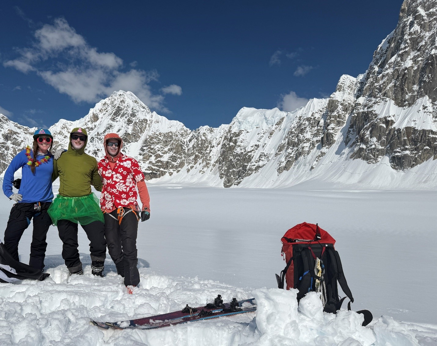 3 rangers linked arm in arm pose in front of a mountain ridgeline and a blue sky