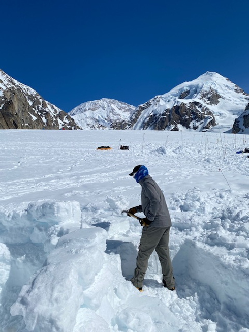 A volunteer shovels or 'rearranges' snow on a glacier