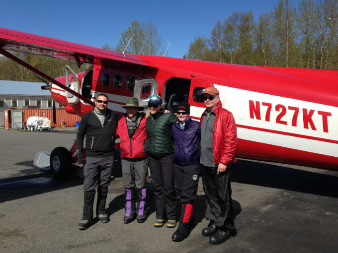 Five climbers pose for a photo outside a small airplane