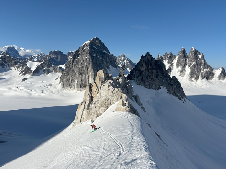 A ranger skies past a mountain peak