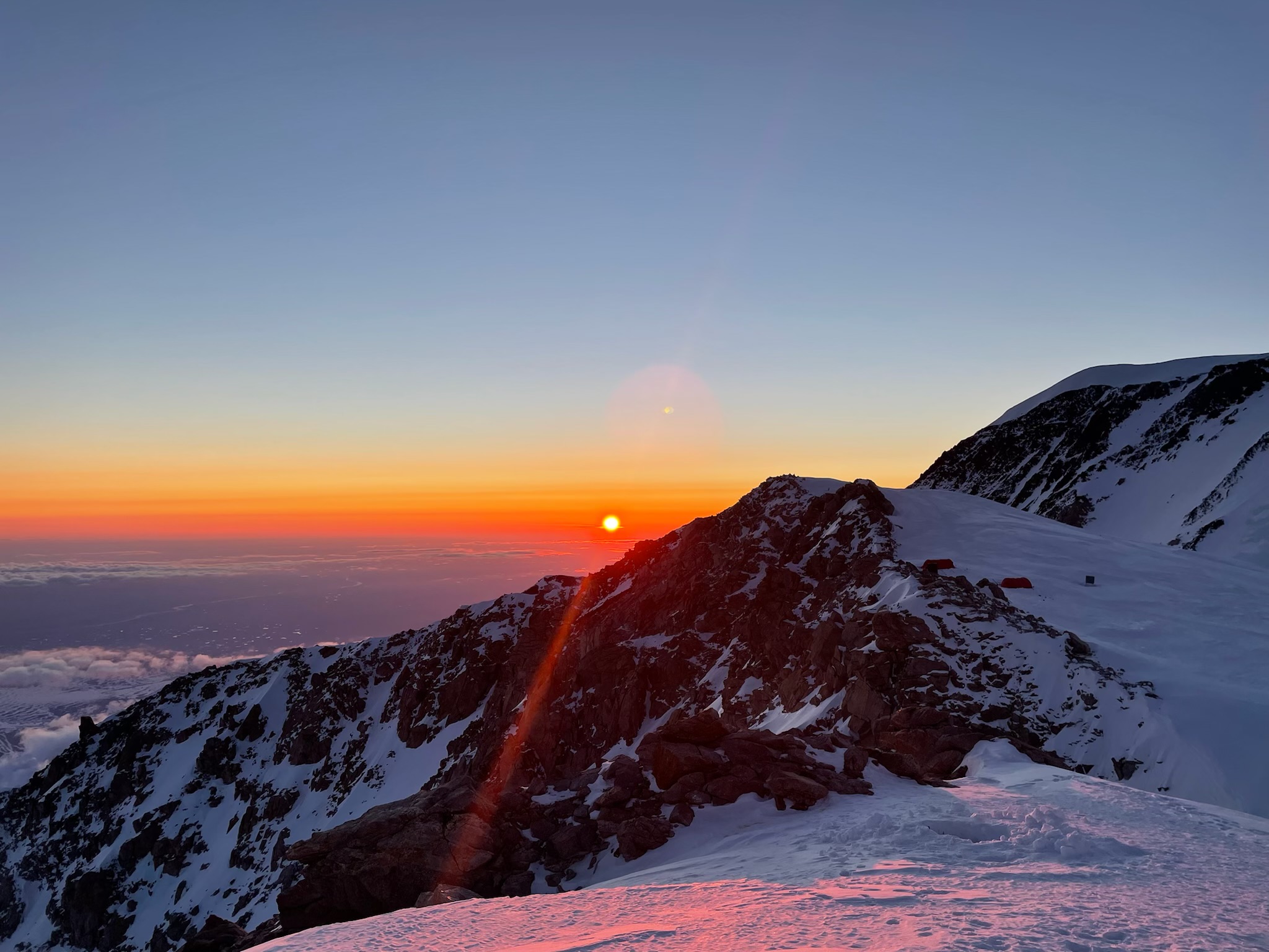 The sun sets behind a mountain ridge