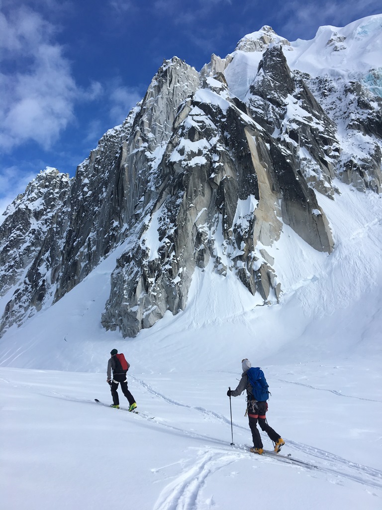 Two rangers ski tour below the rock face known as the Crown Jewel