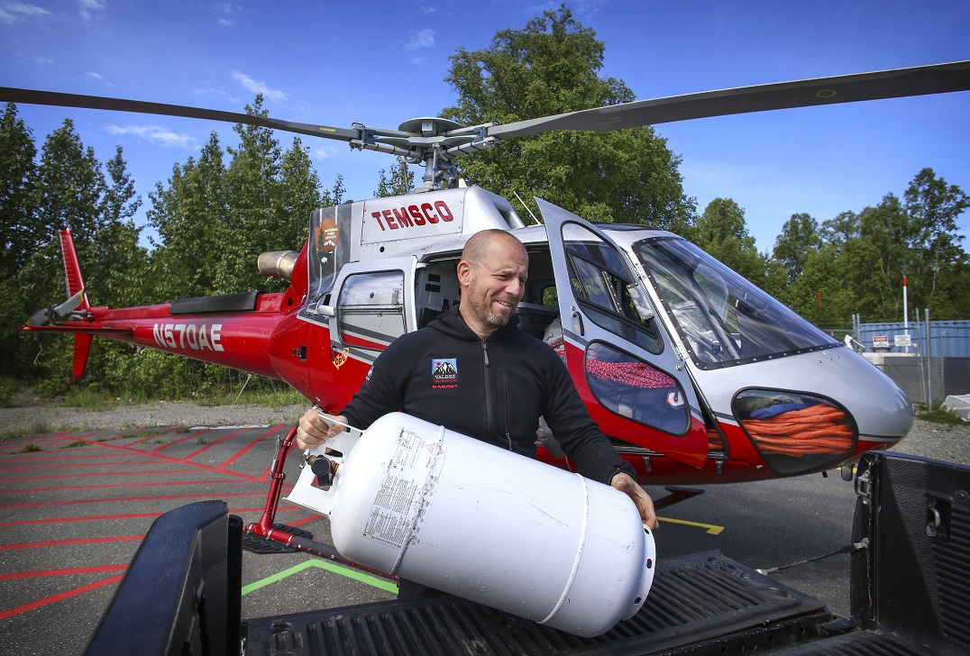 Hermansky unloads a propane tank from the helicopter