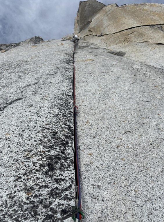 A ranger climbs up a cracked rock face