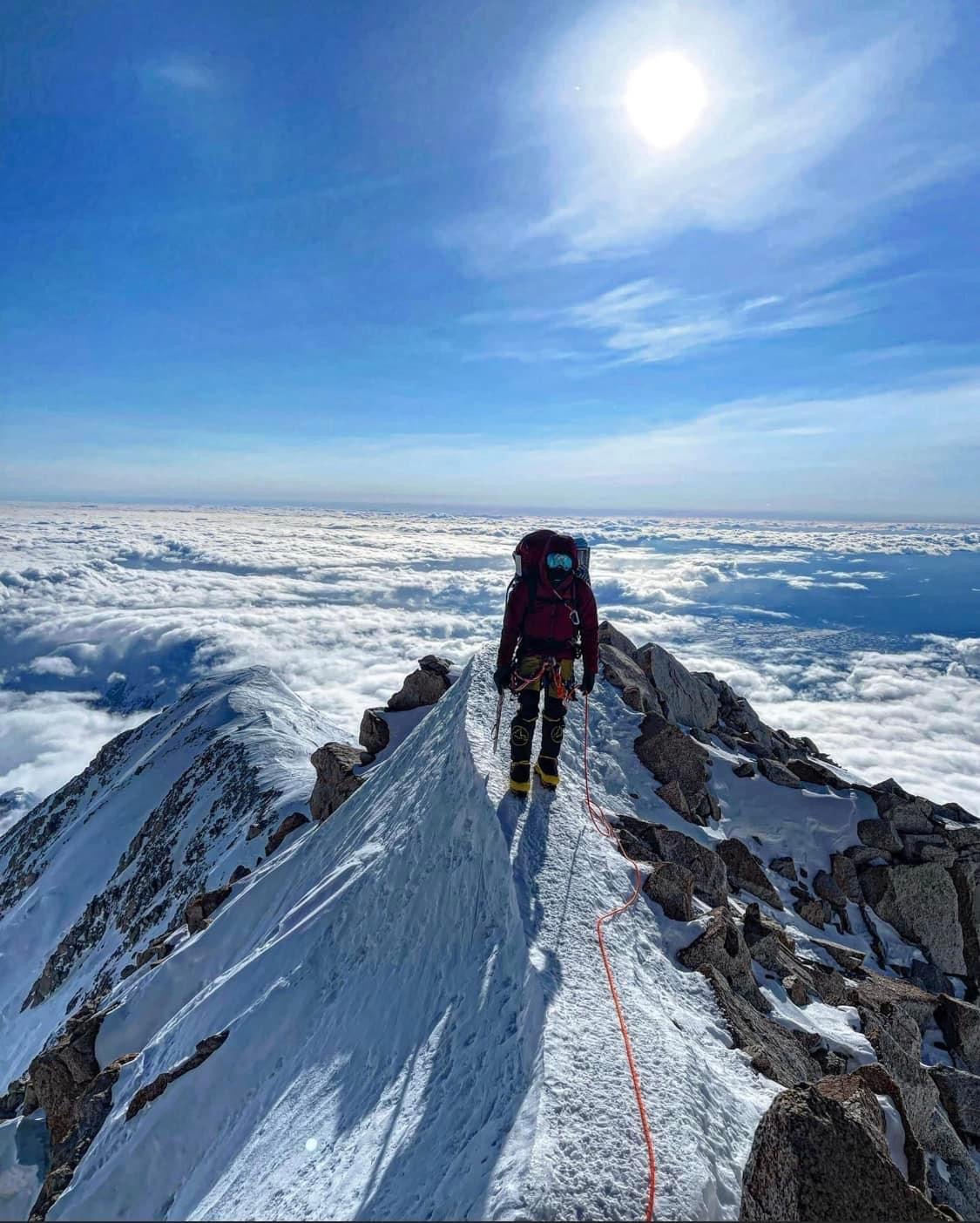 A roped climber walks a narrow ridge